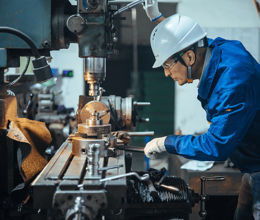Factory worker operating industrial milling machine.